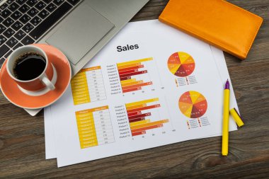 Rapor sayfaları ve kahve makinesi olan ofis çalışma masası.