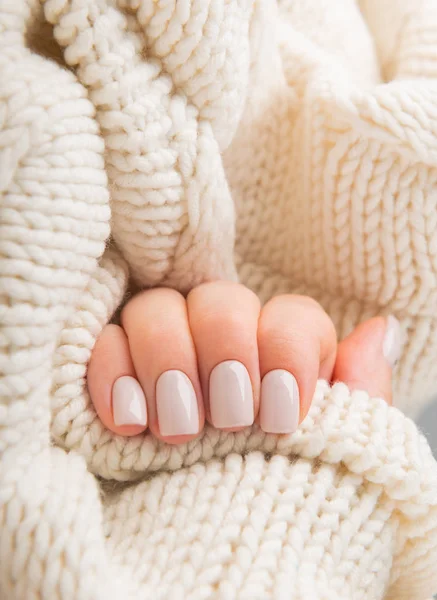 Elegante pastel bege unhas segurando malha de lã materia — Fotografia de Stock