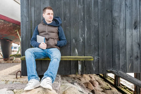 Человек сидит на скамейке перед стеной — стоковое фото