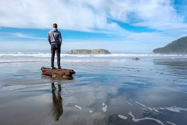 Homme debout sur la bûche à la plage — Photo