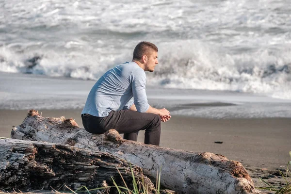 Homme assis près de l'océan — Photo
