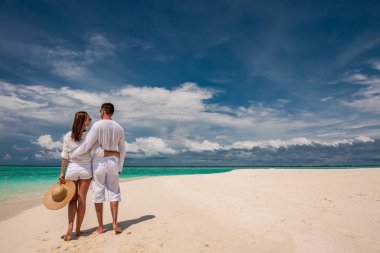 Tropik sahilde yürüyen bir çift.