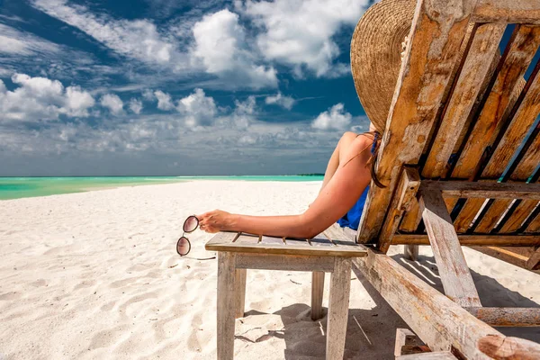 Žena na pláži drží sluneční brýle — Stock fotografie