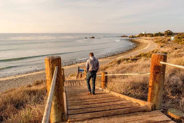Uomo che cammina sul lungomare fino alla spiaggia — Foto Stock