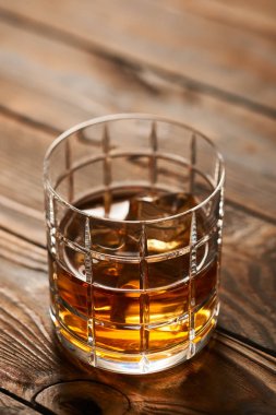 Tahta masada buz küpleri olan bir bardak viski.