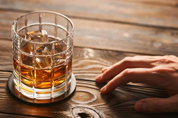 Main masculine atteignant pour le verre avec whisky — Photo