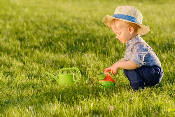 Boy wearing straw hat using watering can — Stock Photo, Image