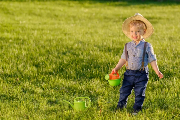 Yürümeye başlayan çocuk açık havada. Bir yaşında sulama olabilir kullanarak hasır şapkalı erkek bebek — Stok fotoğraf