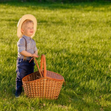 Hasır şapka ve piknik sepeti giyen erkek bebek