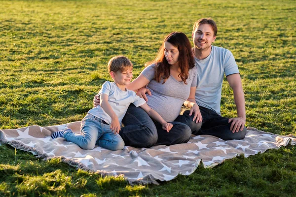 Familia feliz de tres sentados en el parque . — Foto de Stock