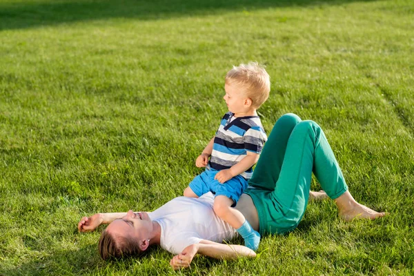 Mujer y el niño se divierten en la hierba — Foto de Stock