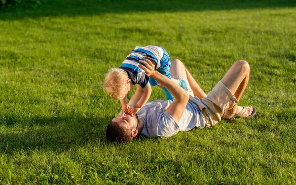 Far och son liggande på gräs — Stockfoto