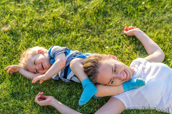 Sorrindo mãe e filho na grama — Fotografia de Stock