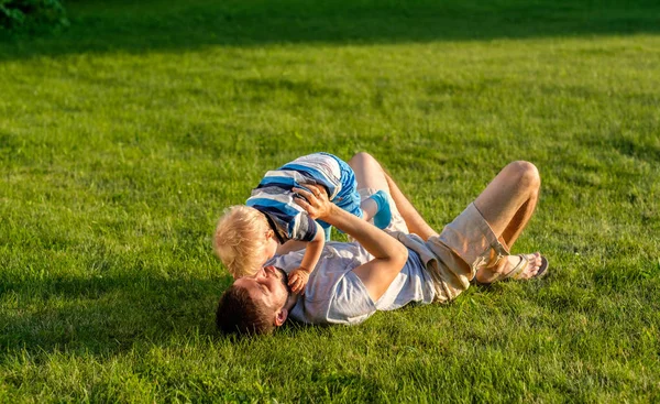 Far och son att ha kul på gräs — Stockfoto