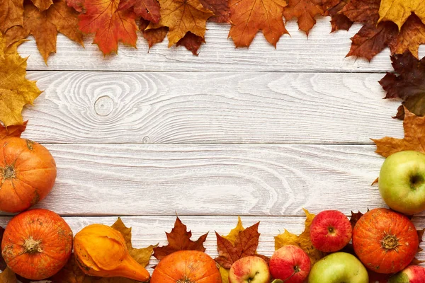 Hojas, manzanas y calabazas sobre fondo de madera — Foto de Stock