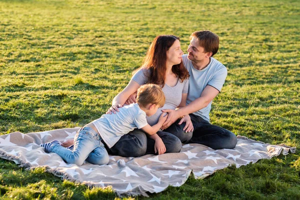 Lycklig familj av tre sitter i parken — Stockfoto