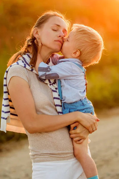 Barn kysser mamma vid solnedgången — Stockfoto