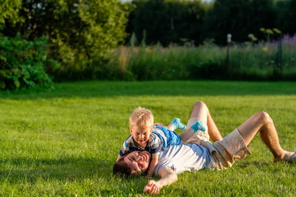 Far och son liggande på gräs — Stockfoto