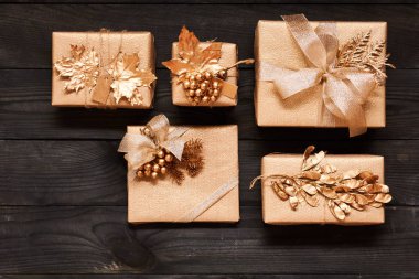 Koyu ahşap arka plan kutularındaki yaratıcı bir şekilde sarılmış ve dekore edilmiş Noel hediyeleri. Üstten Görünüm yukarıdan. Düz yatıyordu. 