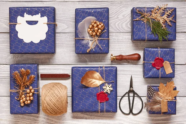 创造性地包装和装饰圣诞礼物在白色的木制背景上的框中 上面的顶视图 — 图库照片