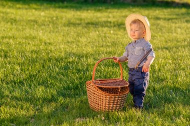 Hasır şapka ve piknik sepeti giyen bir yaşında bir bebek çocuk ile kırsal manzara