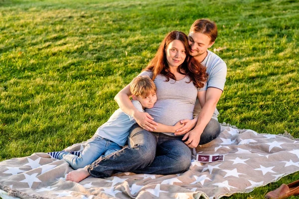 Familia Feliz Tres Esperando Nuevo Bebé Abrazándose Sentado Hierba Verde —  Fotos de Stock