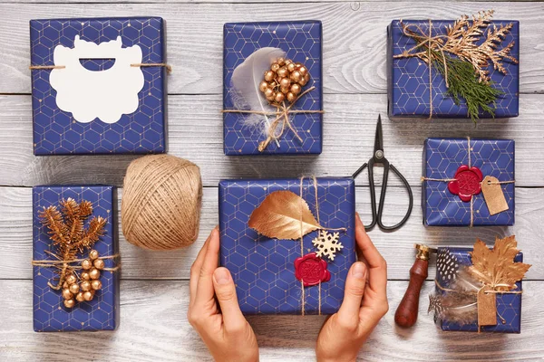 Noel hediyeleri kaydırma kadın. Ahşap arka plan kutularındaki yaratıcı bir şekilde sarılmış ve dekore edilmiş Noel hediyeleri. Üstten Görünüm yukarıdan. Düz yatıyordu. 