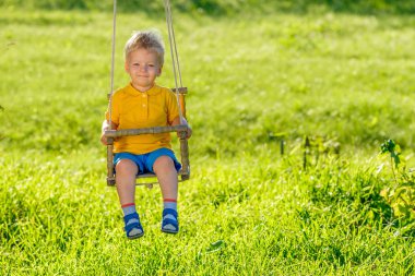 açık havada sallanan küçük sarışın çocuk portresi tam uzunlukta
