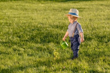 Hasır şapka sulama olabilir kullanarak bir yaşında bir bebek çocuk ile kırsal manzara