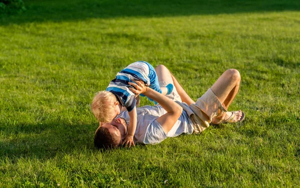 父と一緒に公園に緑の芝生で休んで息子の家族のライフ スタイル シーン — ストック写真