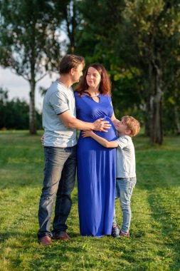 Mutlu hamile Üç Kişilik Aile bebek bekliyor. Açık havada küçük çocuk ile anne ve baba.