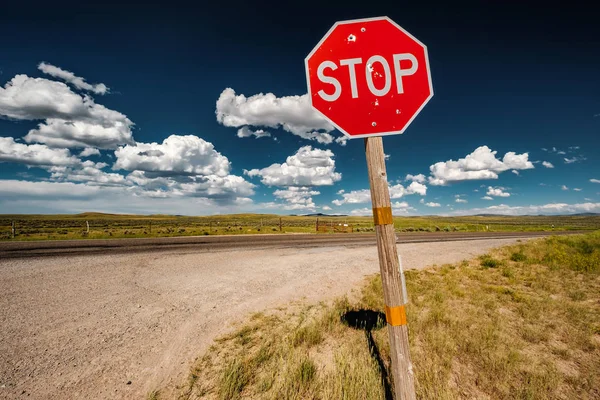 Stop sign with with bullet holes on empty open highway in Wyoming, USA
