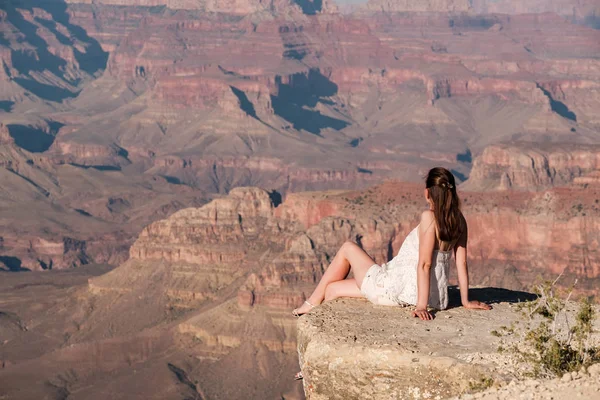 Tourist at Grand Canyon sitting on the rock edge, Arizona, USA