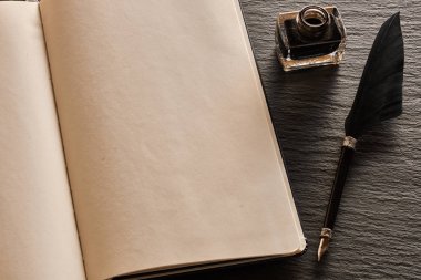 Tüy kalem ve arduvaz arka plan üzerinde boş defter sayfası