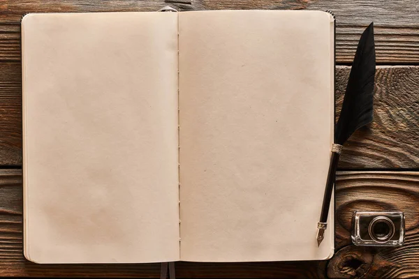 羽ペンと空白のノートブック ページの余分の木製の背景 — ストック写真