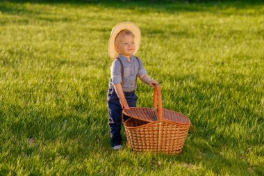 Piknik sepeti ile hasır şapka giyen yürümeye başlayan çocuk