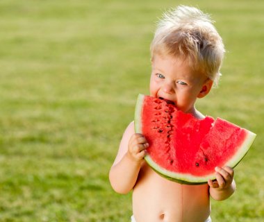 Yürümeye başlayan çocuk açık havada portresi. Karpuz dilimi bahçede yemek bir yaşında bir bebek çocuk ile kırsal sahne. Mutlu bir çocukluk kirli pis yüzü.