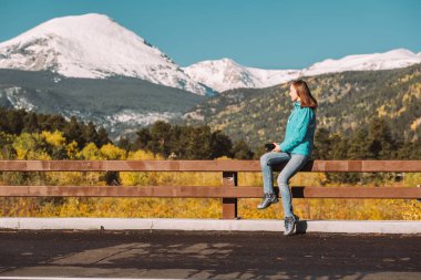 Woman tourist taking photo. Season changing from autumn to winter. Rocky Mountains, Colorado, USA.  clipart