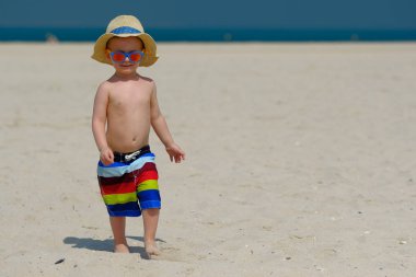 Plajda çalışan güneş şapkalı iki yaşında yürümeye başlayan çocuk 