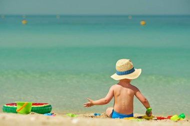 Sahilde plaj oyuncakları ile oynarken iki yaşında bir yürümeye başlayan çocuk 