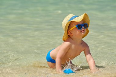 Sahilde plaj oyuncakları ile oynarken iki yaşında bir yürümeye başlayan çocuk 