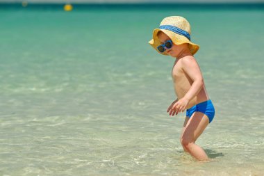 Sahilde yürüyüş güneş şapkalı şirin yürümeye başlayan çocuk 