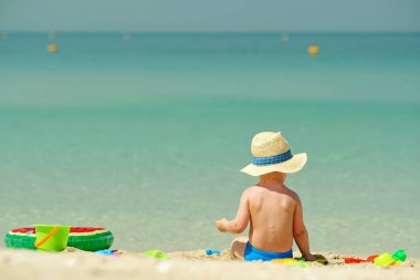 Sahilde plaj oyuncakları ile oynarken iki yaşında bir yürümeye başlayan çocuk 