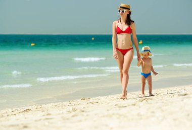 İki yaşındaki yürümeye başlayan çocuk annesi ile Sahilde yürüyüş 