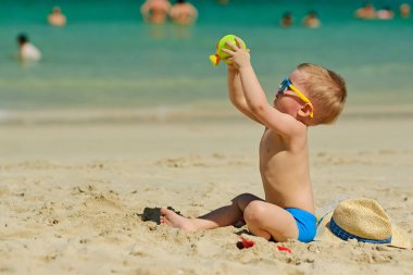 Sahilde plaj oyuncakları ile oynarken iki yaşında bir yürümeye başlayan çocuk 