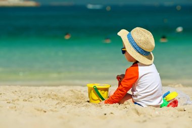 Sahilde plaj oyuncakları ile oynarken iki yaşında bir yürümeye başlayan çocuk 