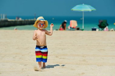 Plajda çalışan güneş şapkalı iki yaşında yürümeye başlayan çocuk 