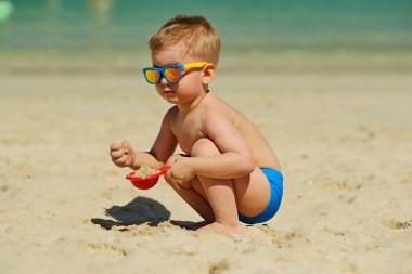 İki yıl yaşlı yürümeye başlayan çocuk ile oynarken kürek ve sahilde kum 