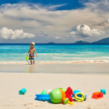 Üç yaşında bir çocuk sahilde plaj oyuncaklarıyla oynuyor. Seyşeller 'de yaz tatili, Mahe..