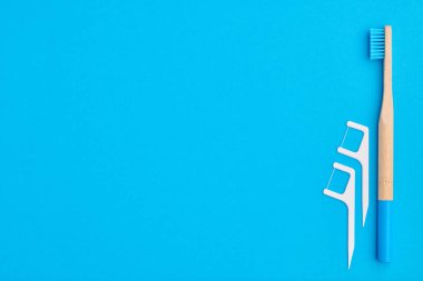Diş fırçaları ve oral bakım araçları mavi arka plan üst görünüm fotokopi alanı düzlüğü üzerinde. Diş bakımı, diş hijyeni ve sağlık konsepti. 